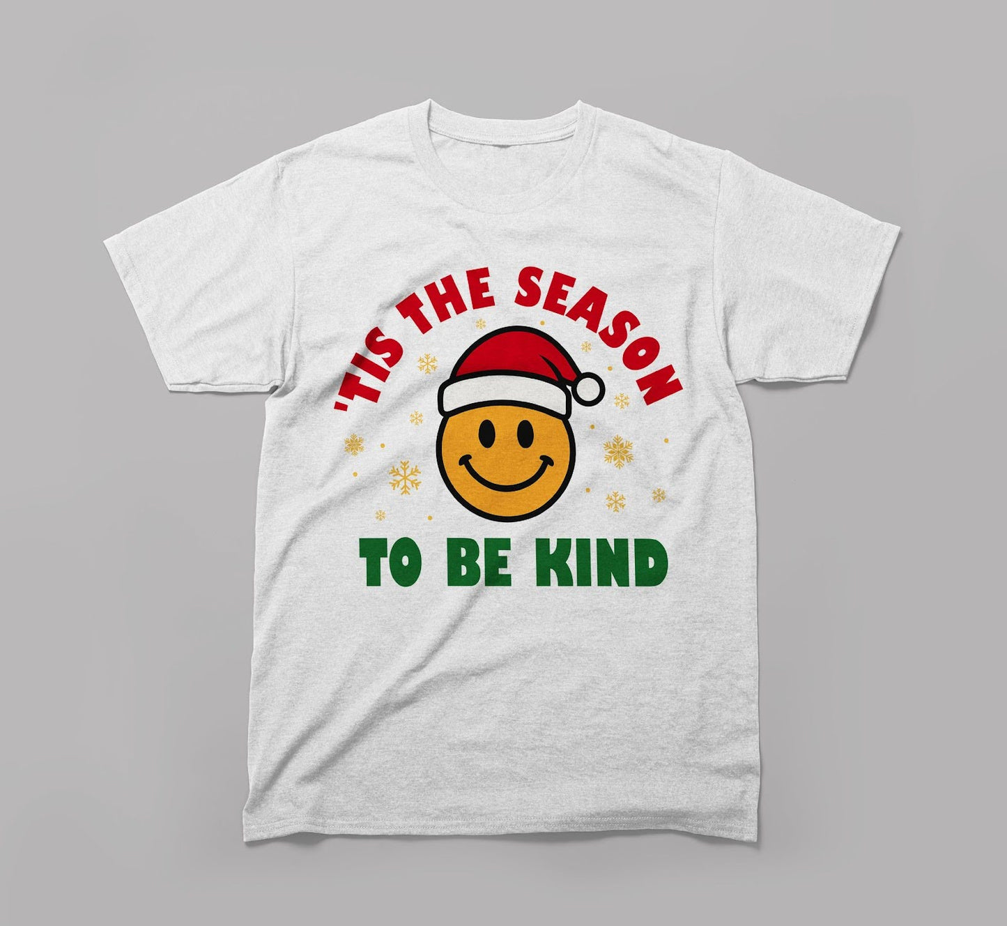 white t-shirt with a smiley face in a santa hat, text 'tis the season to be kind, festive theme