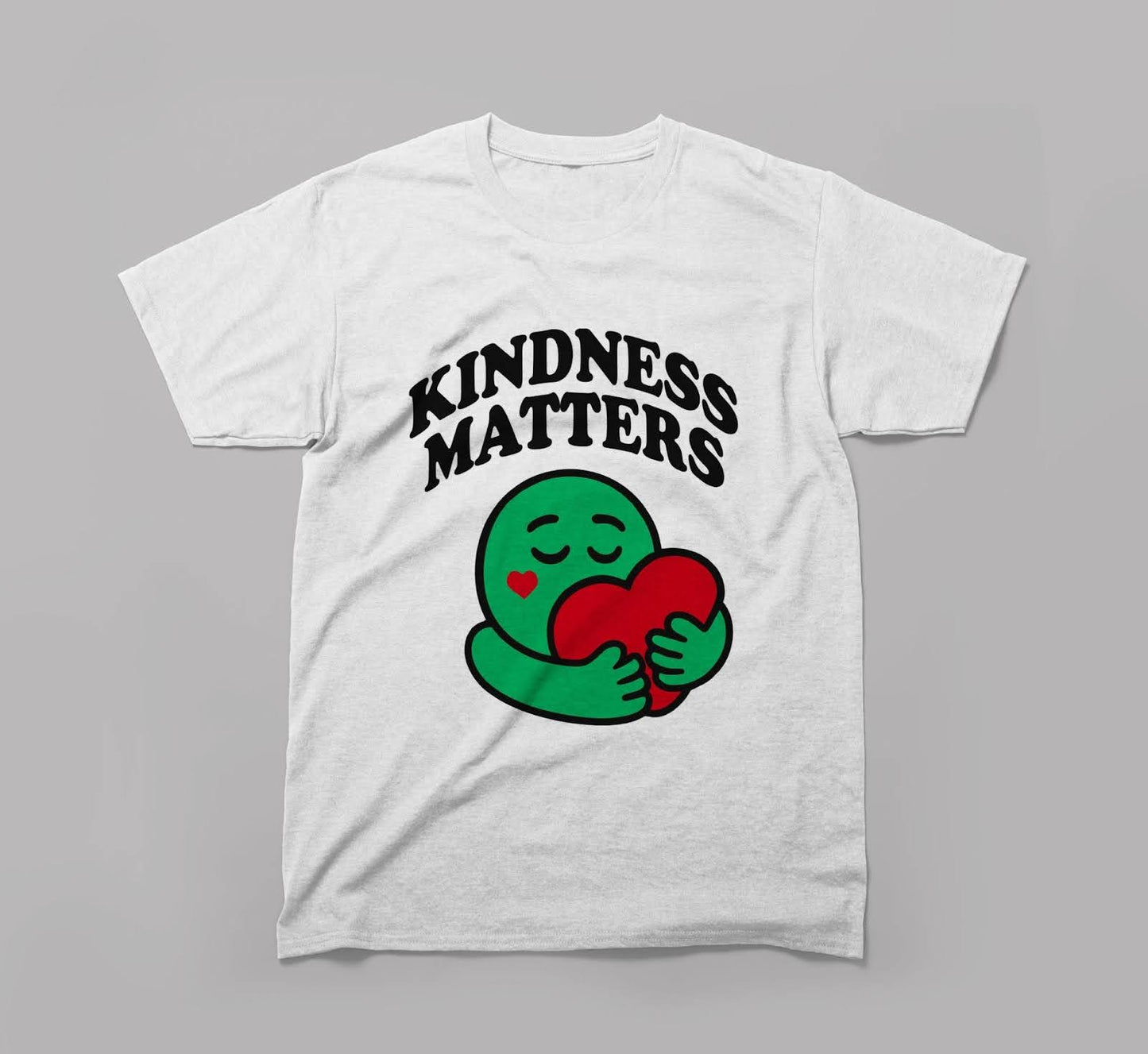 white t-shirt with 'kindness matters' text and green cartoon hugging red heart graphic