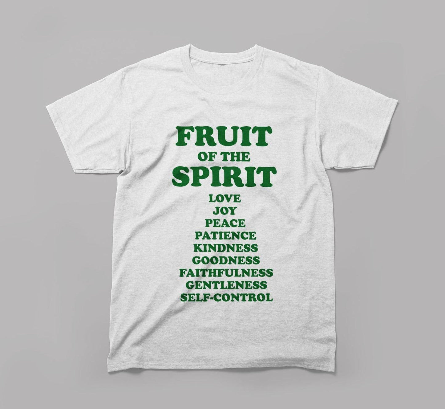 white t-shirt with green text listing fruit of the spirit virtues on a plain gray background.